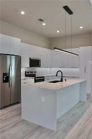 Kitchen with light wood finished floors, stainless steel appliances, a sink, visible vents, and modern cabinets