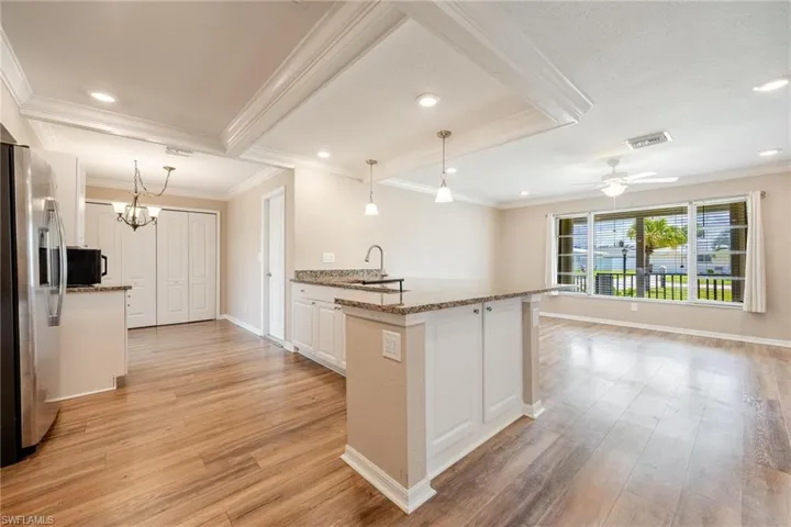 Kitchen featuring light hardwood / wood-style flooring, white cabinets, crown molding, ceiling fan with notable chandelier, and stainless steel refrigerator with ice dispenser