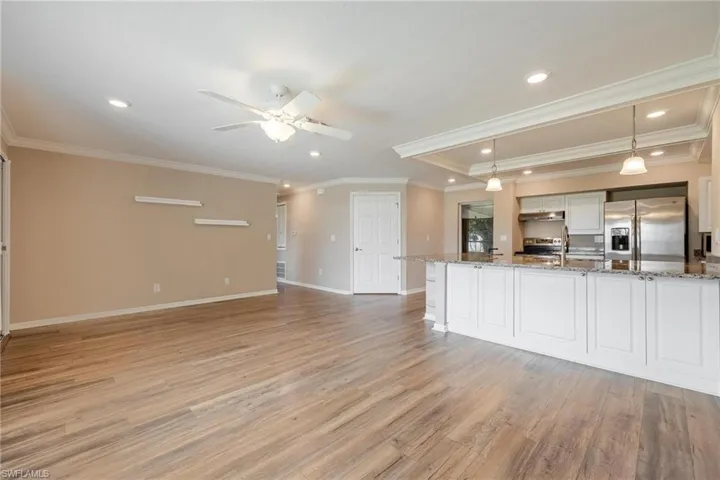 Living room with vinyl plank flooring facing kitchen with granite counter tops.