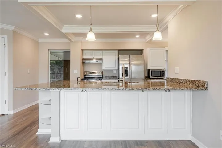 Kitchen with white cabinetry, crown molding, granite counter tops and stainless steel appliances.