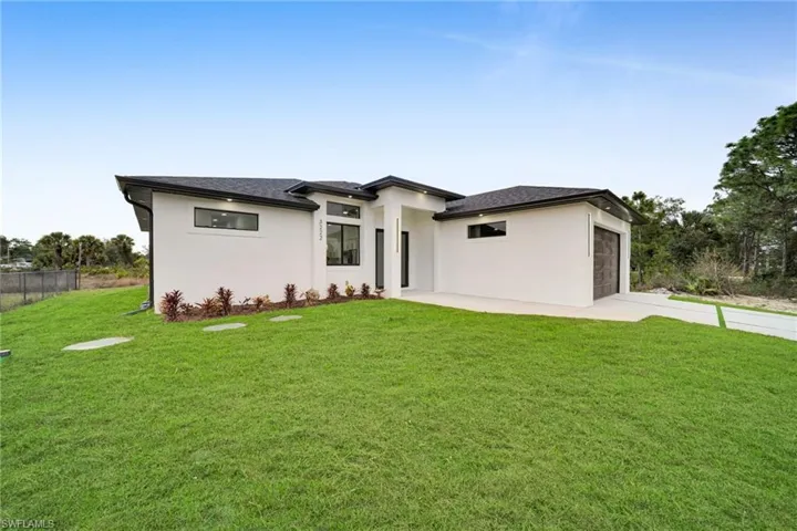Prairie-style home featuring stucco siding, driveway, roof with shingles, and an attached garage