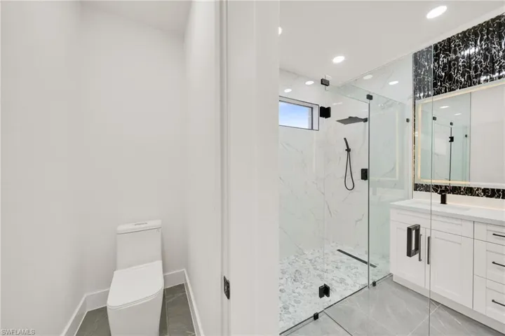 Full bath with vanity, a marble finish shower, and recessed lighting