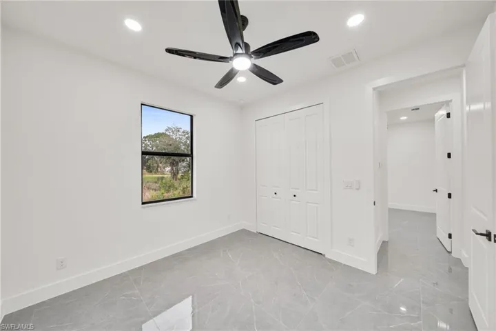 Unfurnished bedroom with recessed lighting, a closet, a ceiling fan, and light marble finish flooring