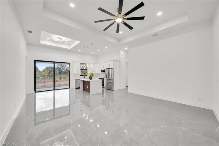 Unfurnished living room with light marble finish floors, recessed lighting, and a raised ceiling