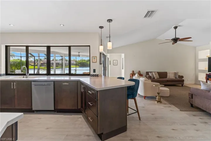 Kitchen with dark brown cabinetry, open floor plan, a peninsula, a breakfast bar area, and a ceiling fan