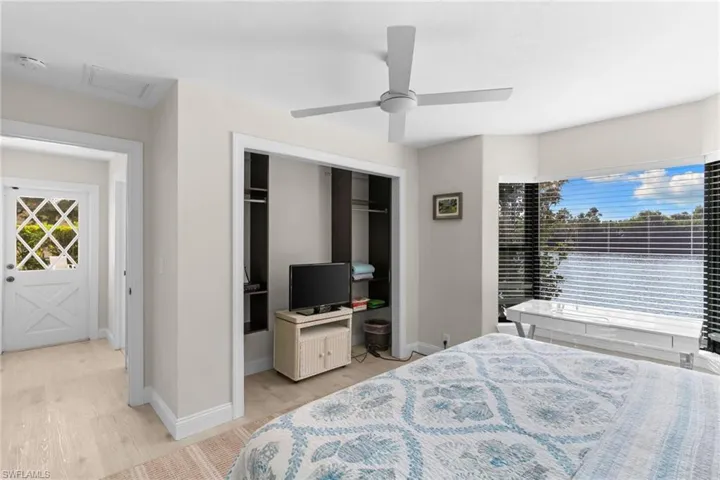 Bedroom with multiple windows, light wood-style flooring, ceiling fan, and a closet