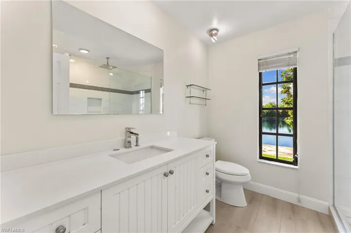 Bathroom featuring a tile shower, vanity, a water view, and light wood-style floors