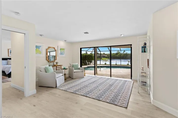 Living room featuring light wood-style flooring, a sunroom, and a water view