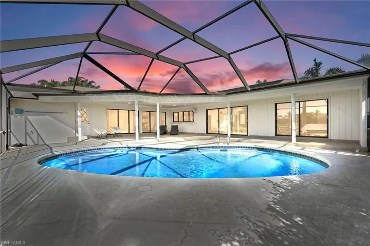 Swimming pool with a sunroom, glass enclosure, and a patio area
