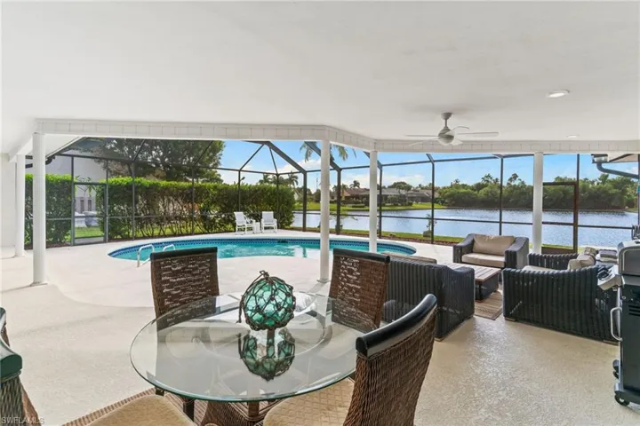 Swimming pool with a lanai, a sunroom, a patio area, a water view, and outdoor dining space