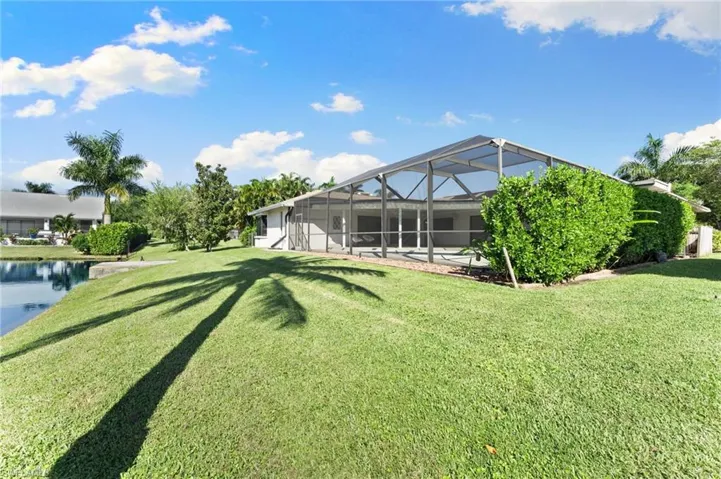 View of grassy yard featuring a lanai, a sunroom, and a water view
