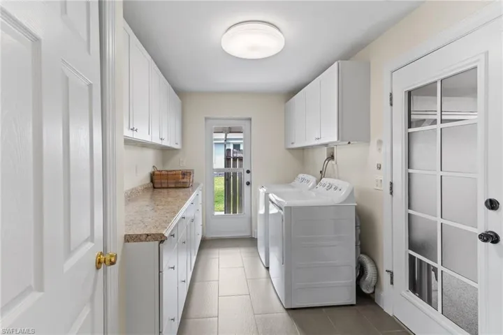Washroom with cabinet space, separate washer and dryer, and light tile patterned floors