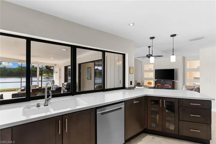 Kitchen featuring dark brown cabinets, dishwasher, open floor plan, pendant lighting, and recessed lighting