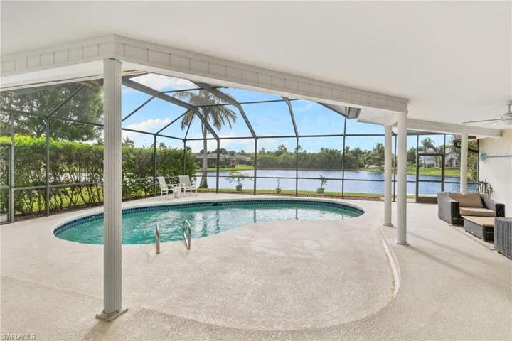 Swimming pool with glass enclosure, a sunroom, a patio, and a water view