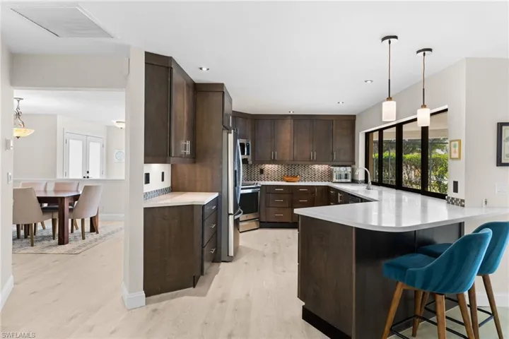 Kitchen featuring pendant lighting, dark brown cabinetry, a kitchen bar, a peninsula, and light wood finished floors
