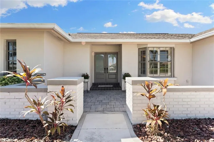 View of exterior entry with stucco siding and french doors