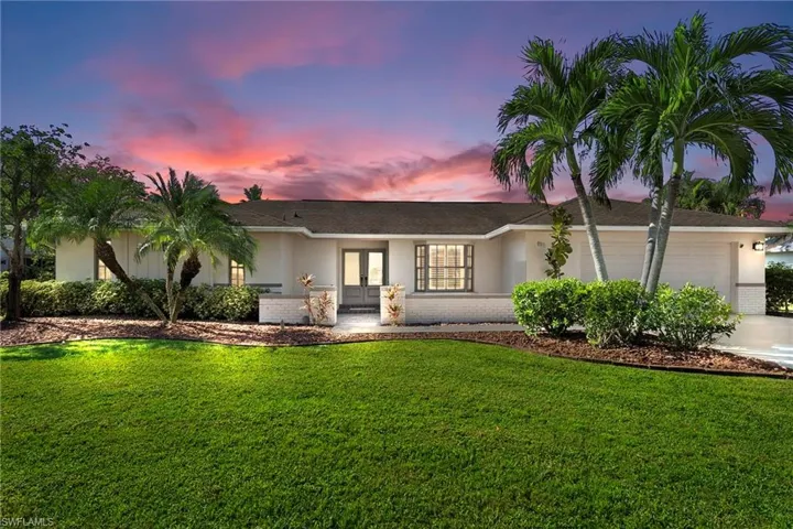 Ranch-style home featuring stucco siding, french doors, a front yard, and a garage