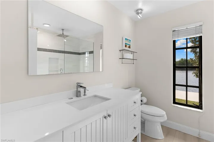 Full bathroom featuring a shower stall, vanity, a water view, and light wood finished floors
