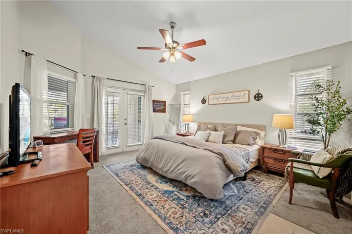 Bedroom featuring an office area, vaulted ceiling, french doors, access to exterior, and light colored carpet