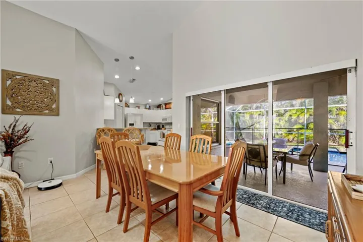 Dining space featuring high vaulted ceiling, light tile patterned floors, and recessed lighting