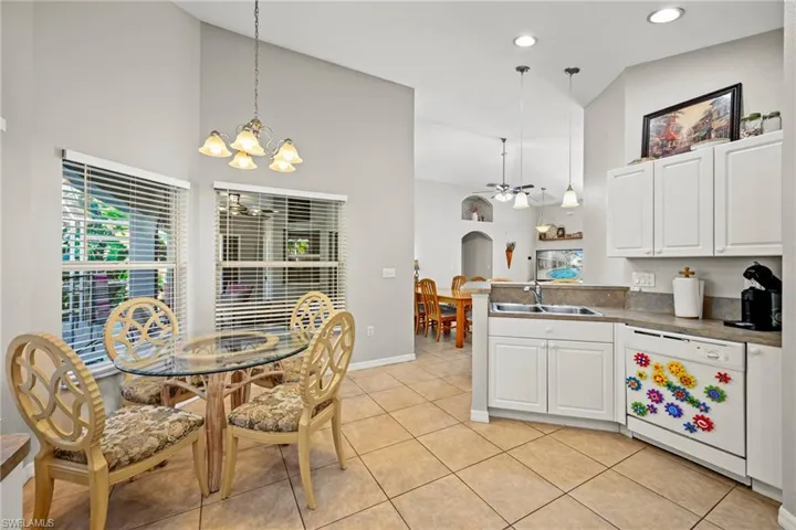 Kitchen featuring dishwasher, white cabinets, decorative light fixtures, arched walkways, and high vaulted ceiling