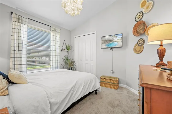 Bedroom with lofted ceiling, light carpet, a closet, and a chandelier