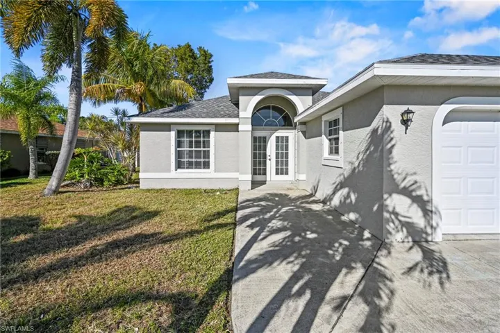 View of front of property with stucco siding, french doors, a garage, and a front yard
