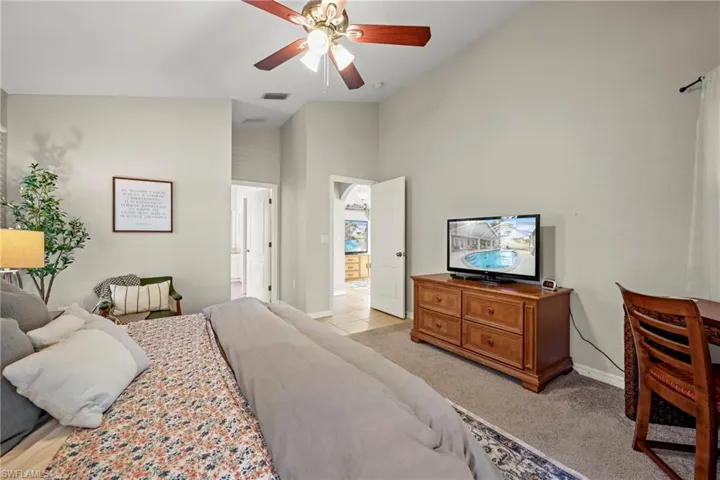 Bedroom featuring high vaulted ceiling, light carpet, and a ceiling fan