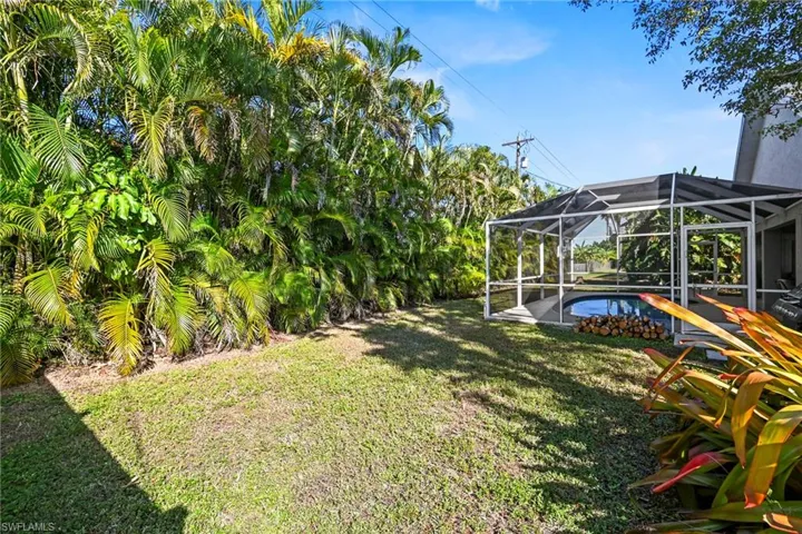 View of green lawn with a lanai, an outdoor pool, a sunroom, and a patio area