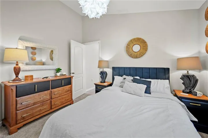 Bedroom featuring light colored carpet and high vaulted ceiling