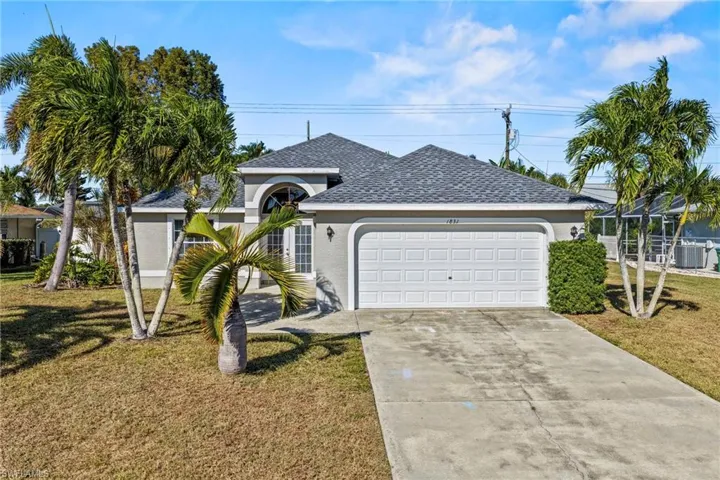 Ranch-style home featuring a front lawn, roof with shingles, stucco siding, and driveway