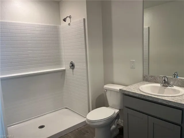 Full bathroom with vanity, a stall shower, and dark wood-style flooring