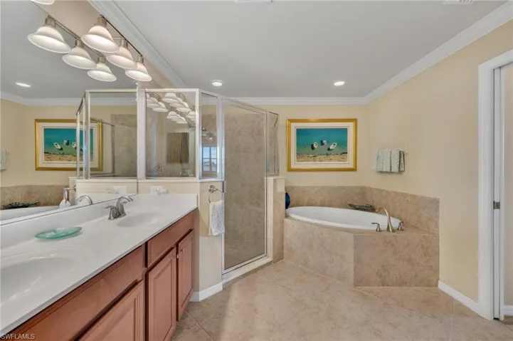 Primary bath featuring double sinks, garden tubs, walk in shower and crown molding