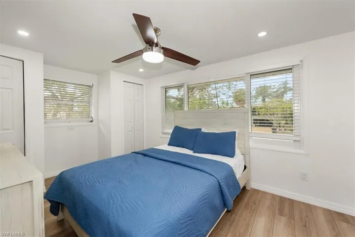 Bedroom with wood finished floors, two closets, recessed lighting, and a ceiling fan