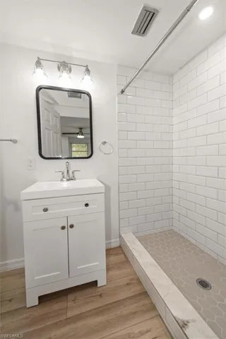 Bathroom featuring a shower stall, vanity, and light wood-style floors