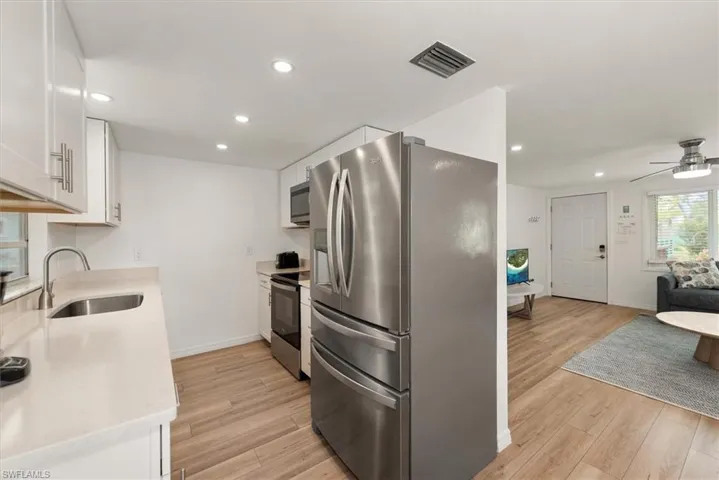 Kitchen with appliances with stainless steel finishes, recessed lighting, white cabinetry, light stone countertops, and a ceiling fan
