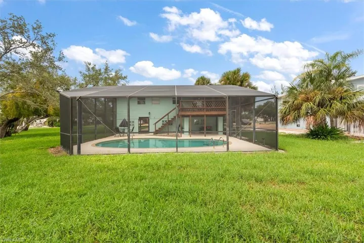 Back of house with a sunroom, glass enclosure, a patio, and a yard