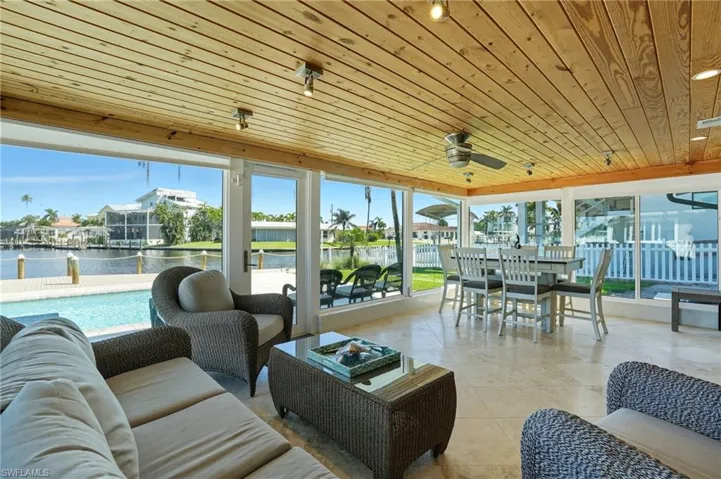 Sunroom with wood ceiling, a water view, and tile patterned floors - Virtually Edited Image