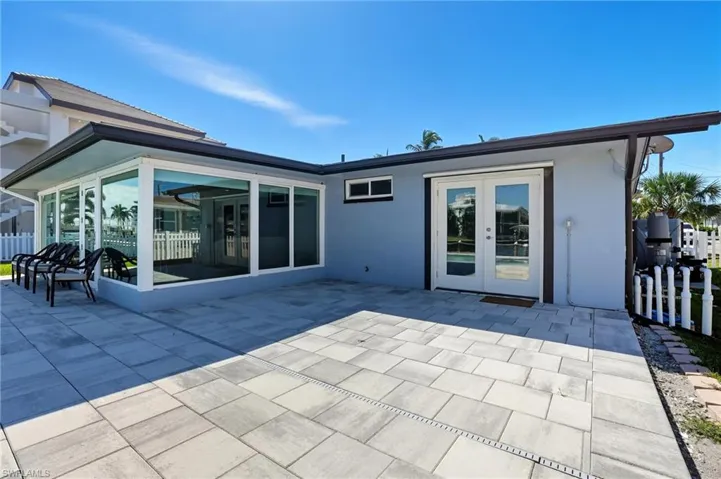 Back of property with a patio area, stucco siding, and french doors - Virtually Edited Image