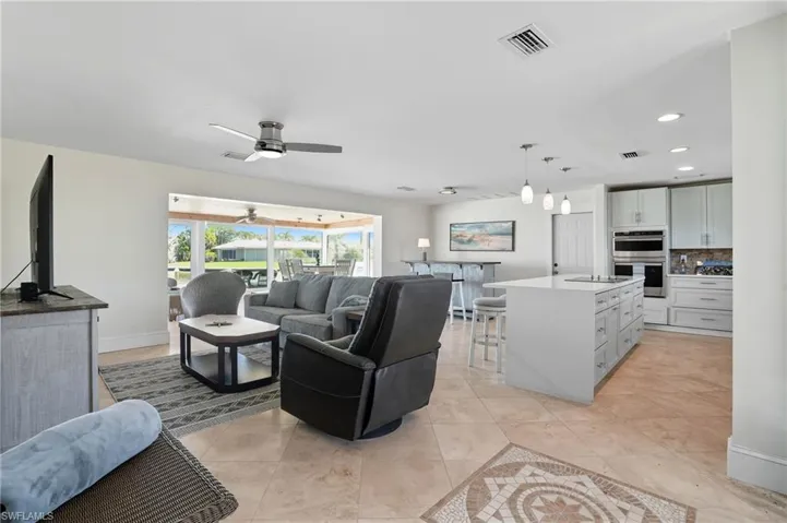 Living room with light tile patterned flooring, recessed lighting, and ceiling fan - Virtually Edited Image