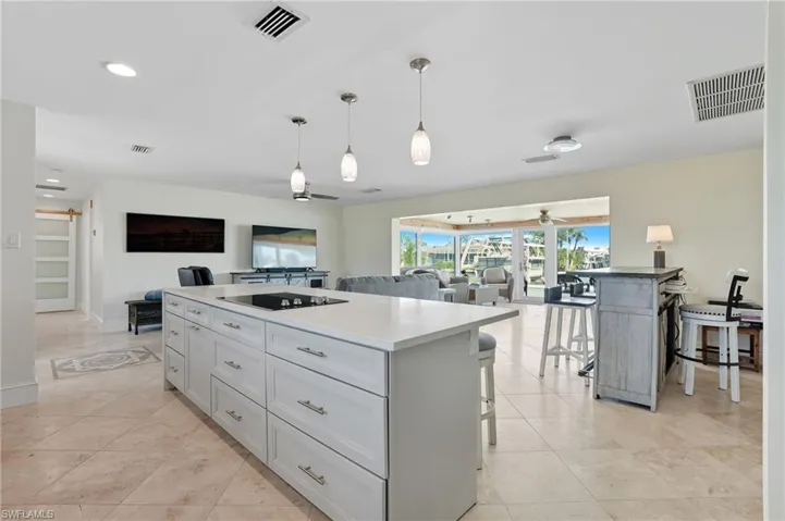 Kitchen with a kitchen island, open floor plan, pendant lighting, a kitchen bar, and recessed lighting - Virtually Edited Image
