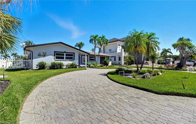 Ranch-style house with curved driveway and stucco siding - Virtually Edited Image