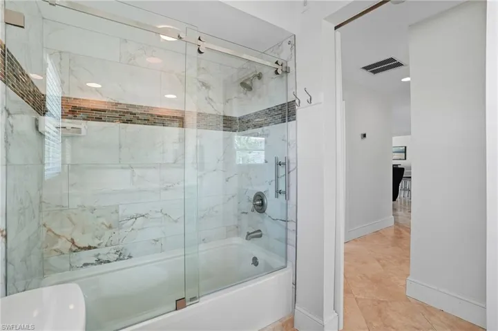 Full bath with enclosed tub / shower combo and tile patterned flooring - Virtually Edited Image