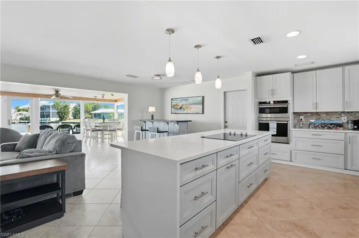 Kitchen with decorative light fixtures, open floor plan, recessed lighting, a center island, and decorative backsplash - Virtually Edited Image