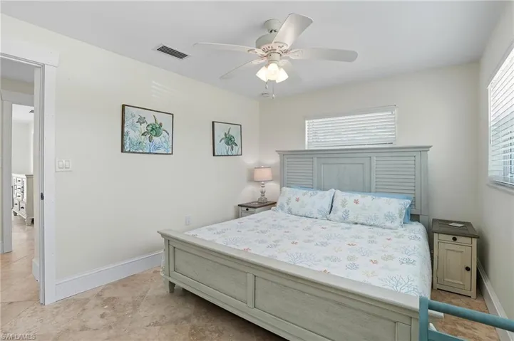 Bedroom featuring multiple windows, a ceiling fan, and light tile patterned floors - Virtually Edited Image