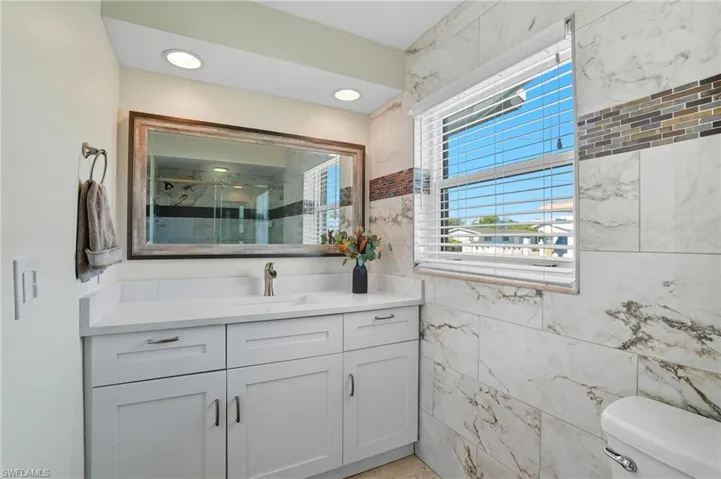 Full bathroom with vanity, a shower stall, and tile walls - Virtually Edited Image