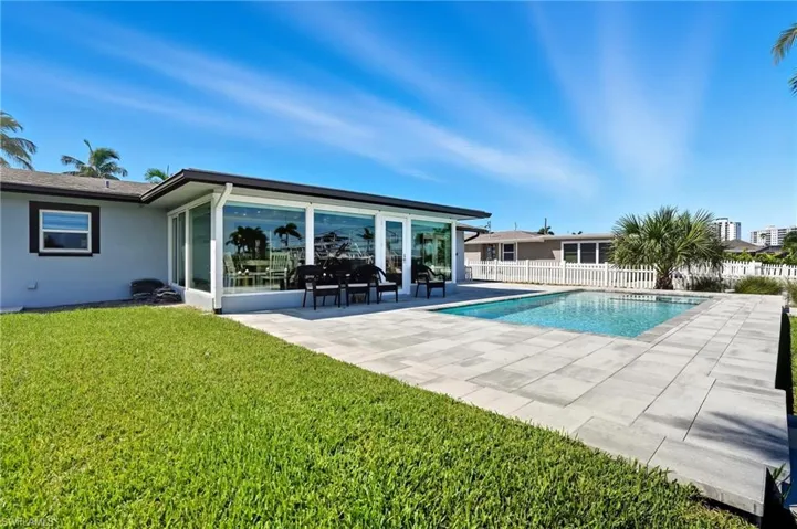 View of swimming pool featuring a patio area, a sunroom, and ceiling fan - Virtually Edited Image