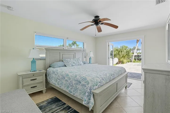 Bedroom with multiple windows, light tile patterned floors, and ceiling fan - Virtually Edited Image