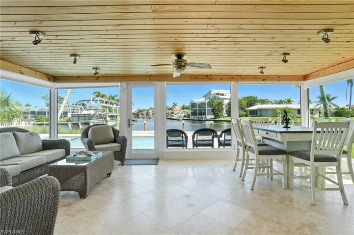 View of patio with ceiling fan, a water view, a sunroom, and an outdoor living space - Virtually Edited Image