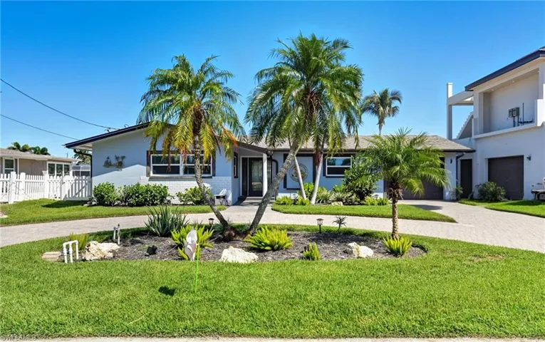 View of front of home with curved driveway, brick siding, and stucco siding - Virtually Edited Image